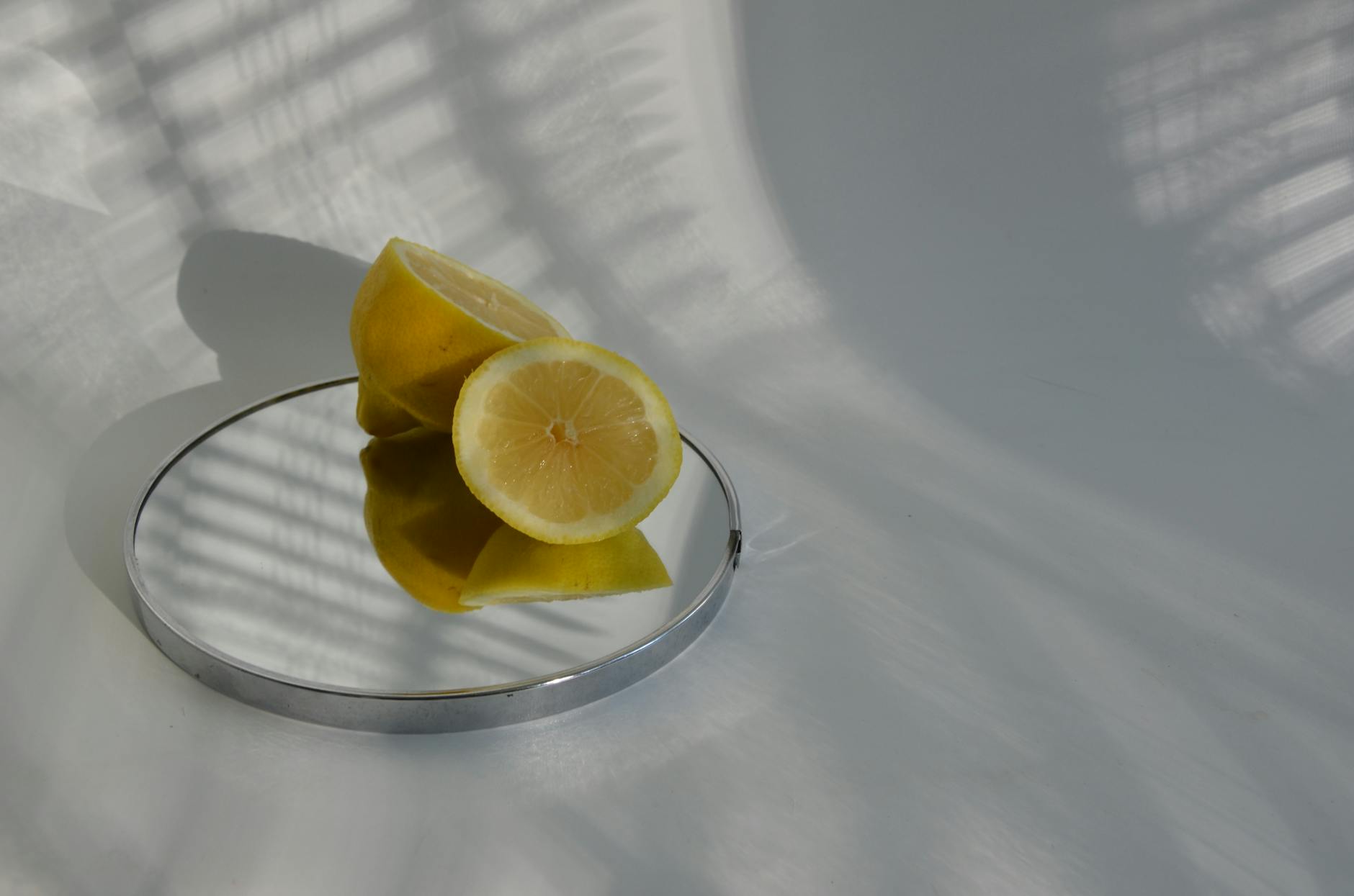 Sliced lemons on a mirror casting shadows in soft light, symbolizing clarity and renewal.