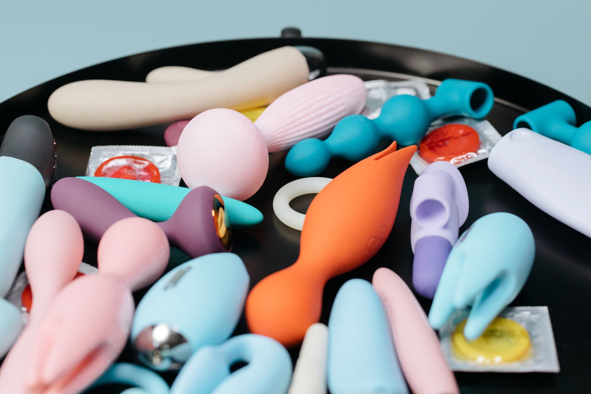 Woman holding blue and pink vibrators, exploring pleasure reconnection options