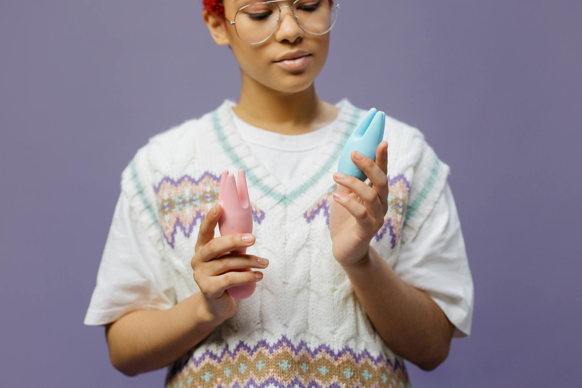Woman holding blue and pink silicone vibrators, exploring pleasure tools after menopause