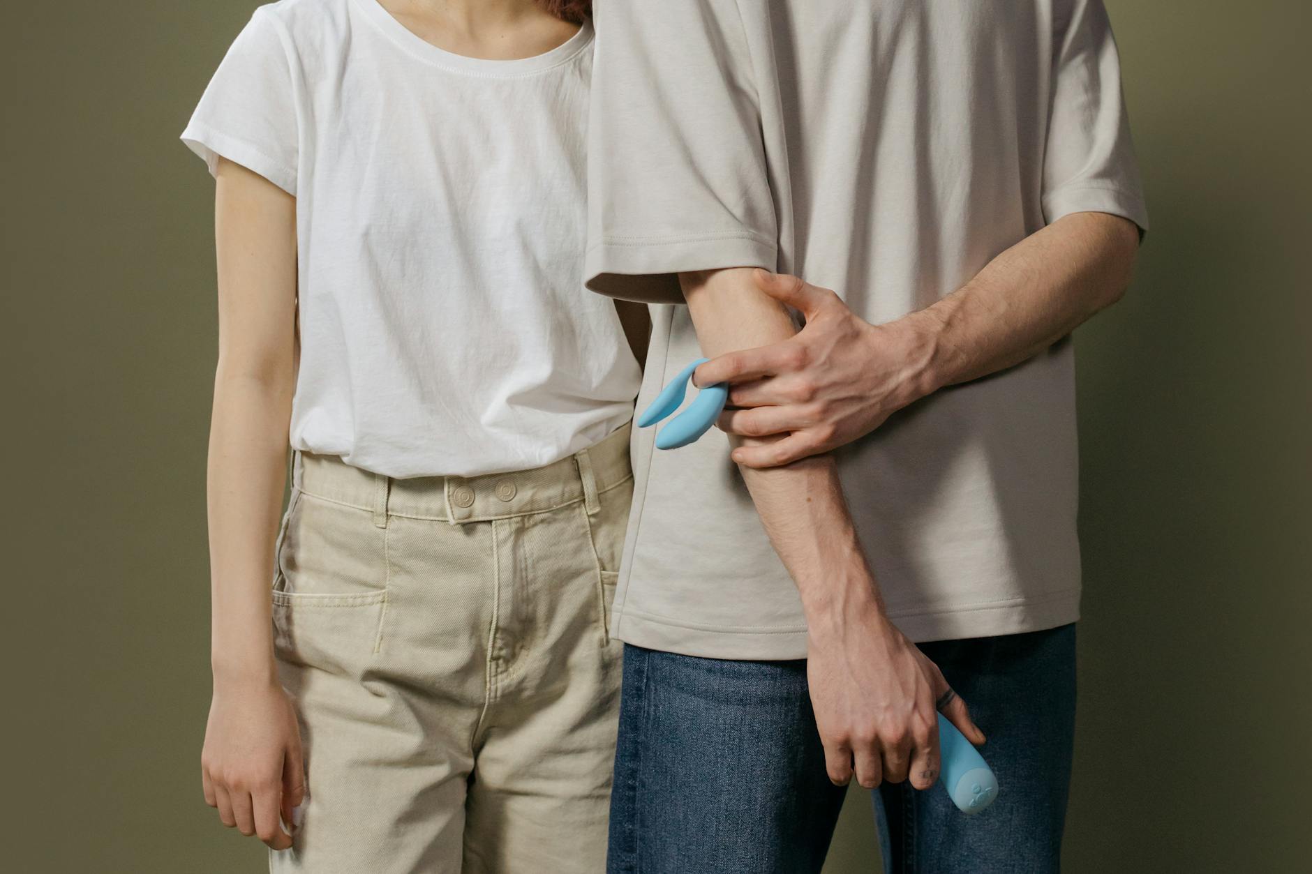 A young couple standing together indoors, exploring intimacy with a modern vibrator