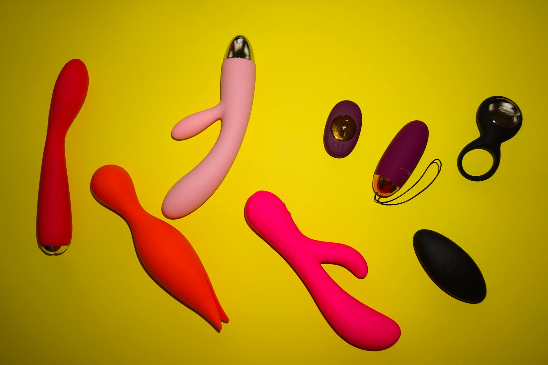 Vibrant display of colorful sex toys on a bright yellow surface, showcasing design diversity
