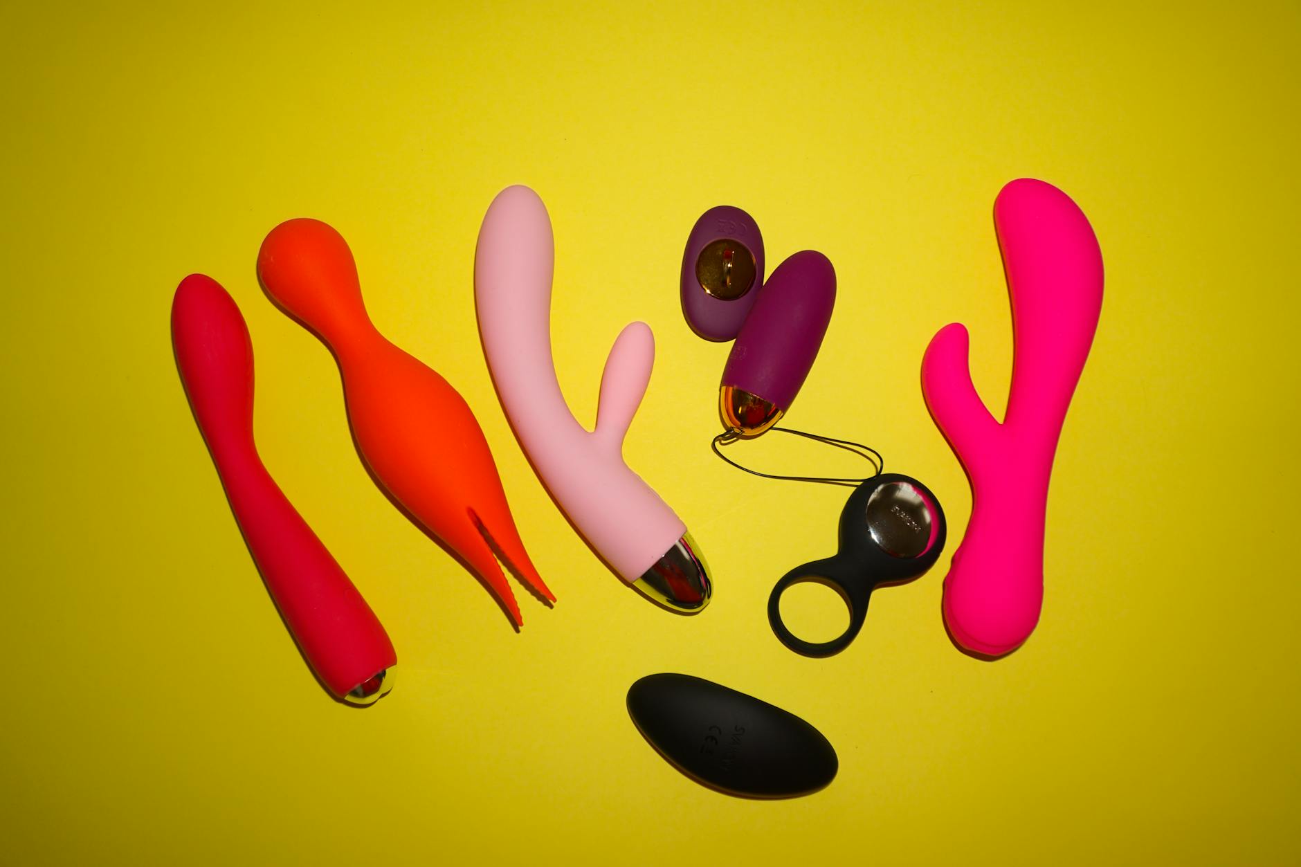 Person holding blue and pink silicone vibrators, considering their options