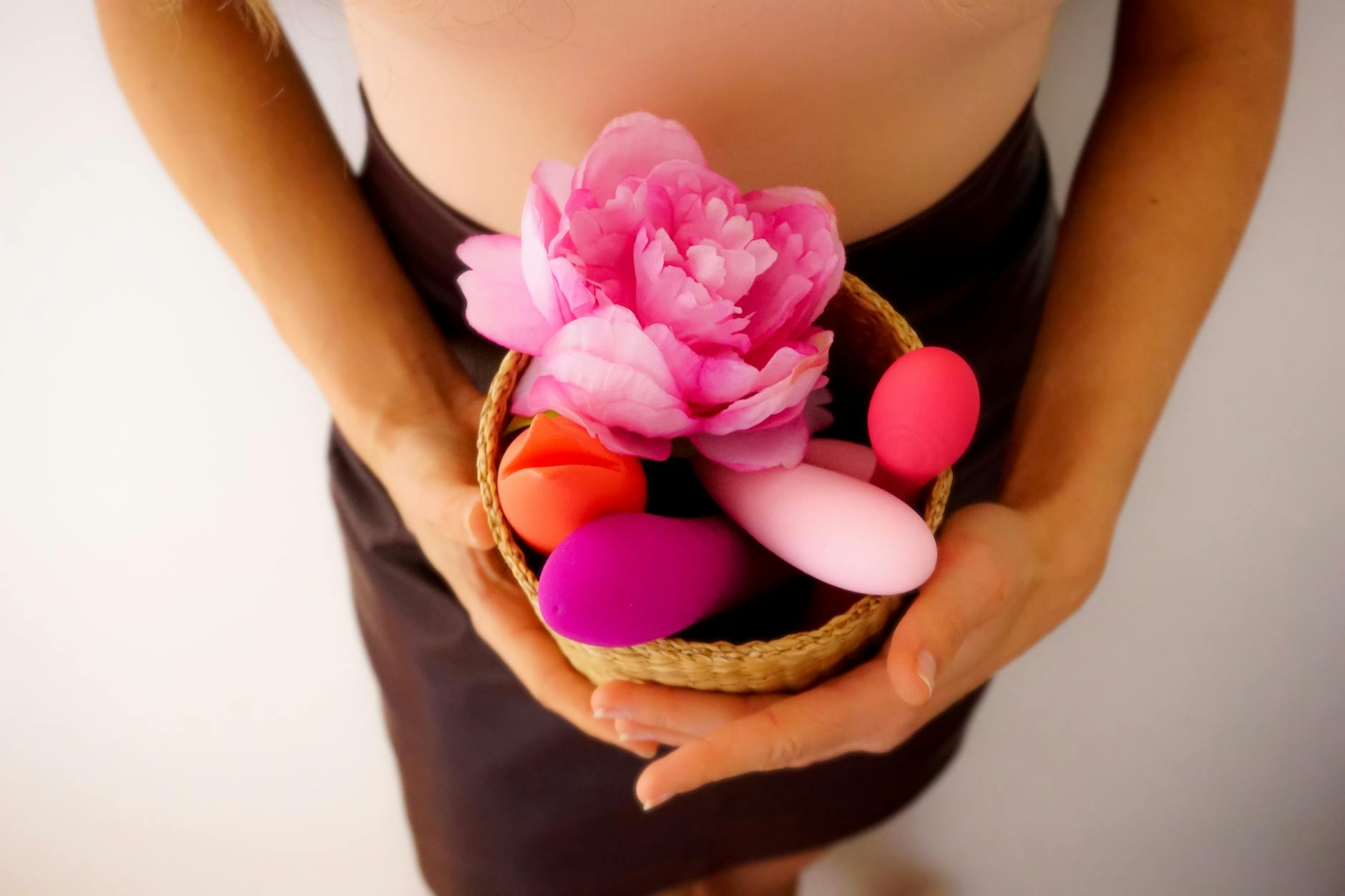 Blue vibrator surrounded by fresh flowers and orange slices on a yellow background